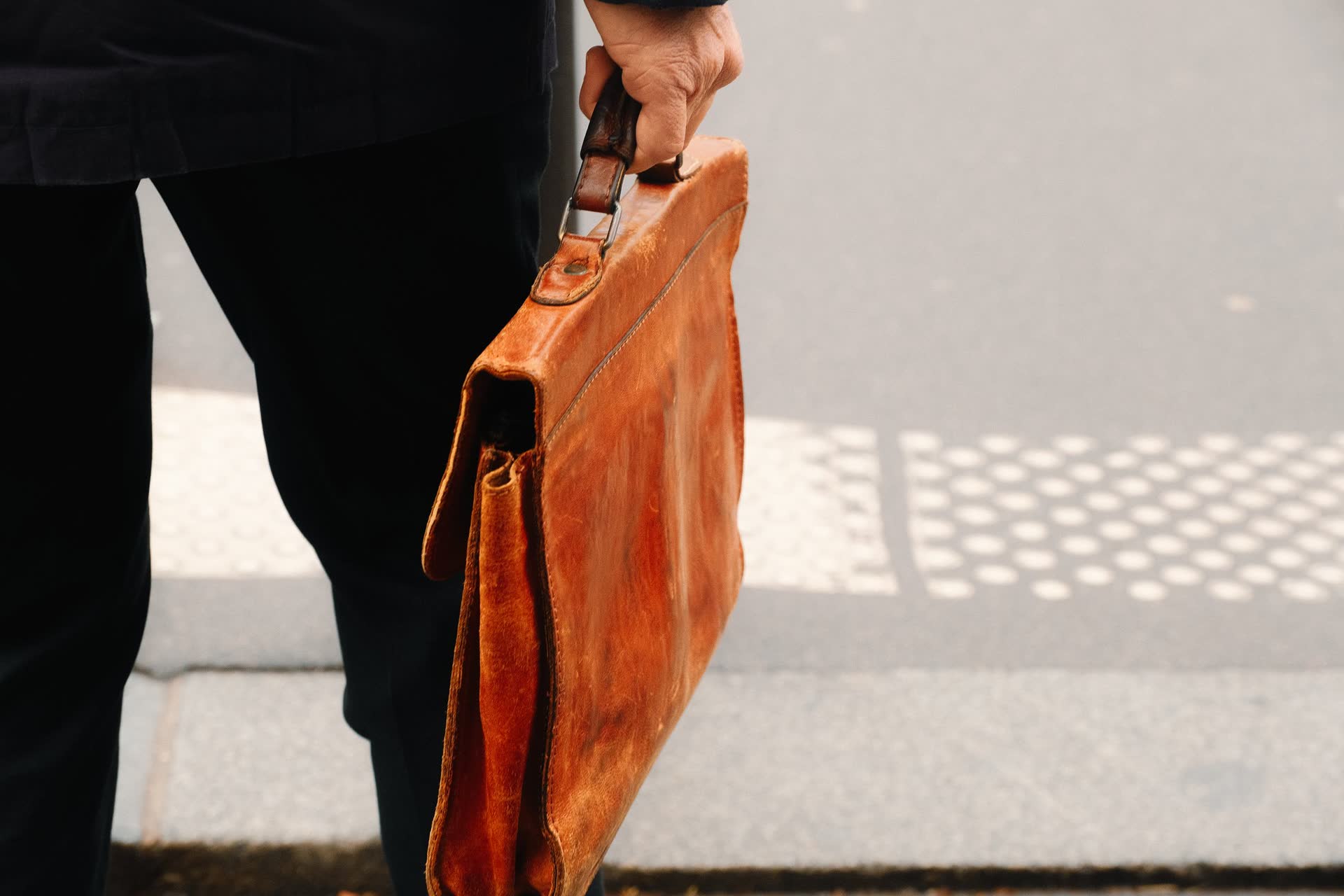 Man walking with a tan leather briefcase
